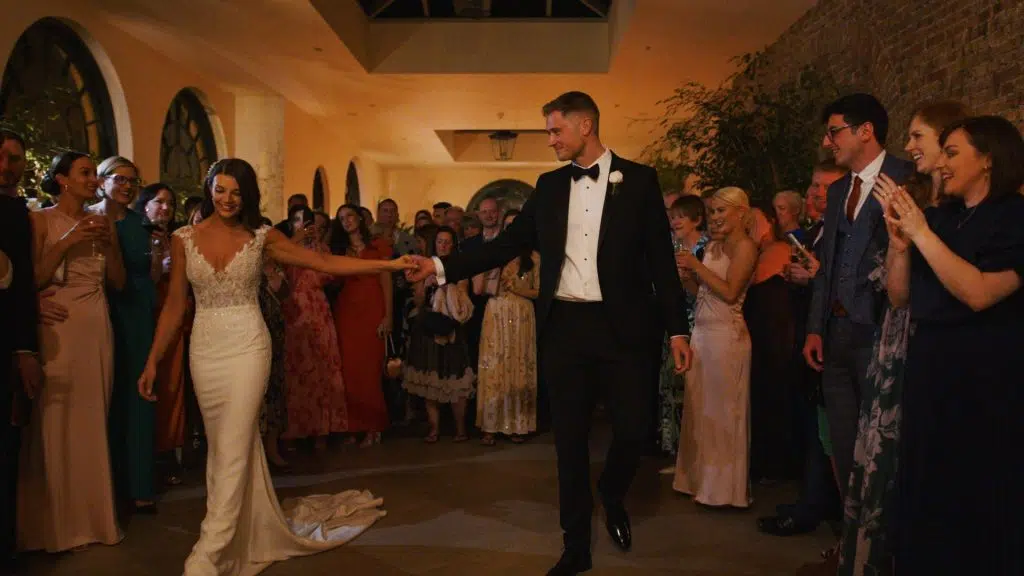 Bride and groom first dance surrounded by guests