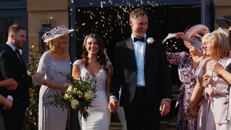 Couple smiling under a confetti shower, joyful moment perfect for cinematic wedding video highlight.