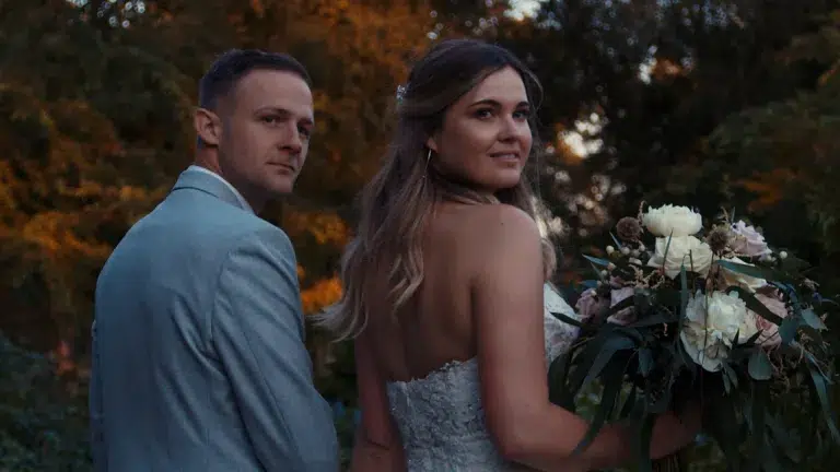 Bride and groom walking hand in hand through countryside at golden hour